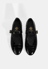 Schwarze Lackleder-Mary-Jane-Schuhe mit einem strukturierten Krokodil-Design, runder Zehenform und verstellbarem Riemen mit goldfarbener Schnalle.