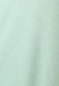 Tessuto verde menta chiaro con una superficie morbida e testurizzata e una fine trama pelosa, adatto per abbigliamento o tessuti per la casa.