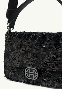 Czarna torebka z cekinami o płaskim designie, z eleganckim srebrnym akcentem logo oraz odpinanym paskiem do różnych opcji noszenia.