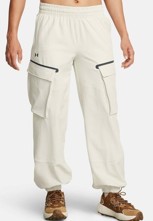 Lys beige cargo bukser med elastisk talje, to store side lommer og sorte detaljer. Båret med brune sportssko.
