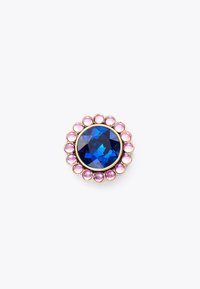 Broche ronde avec un grand bijou bleu entouré d'une bordure ressemblant à des perles roses, monté en métal doré. La surface facettée accentue l'éclat.