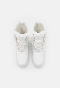 Bottes blanches à lacets avec un extérieur lisse et une doublure en fourrure douce, dotées d'un bout arrondi et de détails cousus sur les côtés.