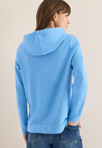 Blauwe katoenen hoodie met trekkoord in de capuchon, lange mouwen en een rechte zoom. De stof heeft een zachte textuur en een comfortabele pasvorm.