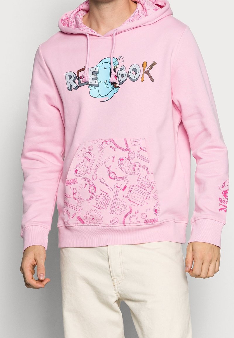 Rosa hoodie med ett grafiskt tryck av en karaktär och texten "REEBOK." Har en mönstrad ficka, dragsnören och ribbade ärmslut.
