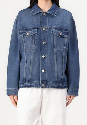 Jeansowa kurtka w średnim niebieskim kolorze o klasycznym kroju, z dwoma kieszeniami na piersi, srebrnymi guzikami i luźnym fasonem. Teksturowane wykończenie materiału.