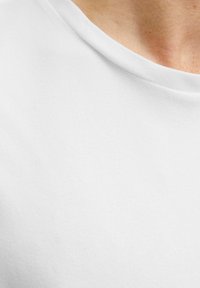 White cotton t-shirt with a soft texture, featuring a round neckline and smooth edges, showing a portion of the collar and shoulder area.
