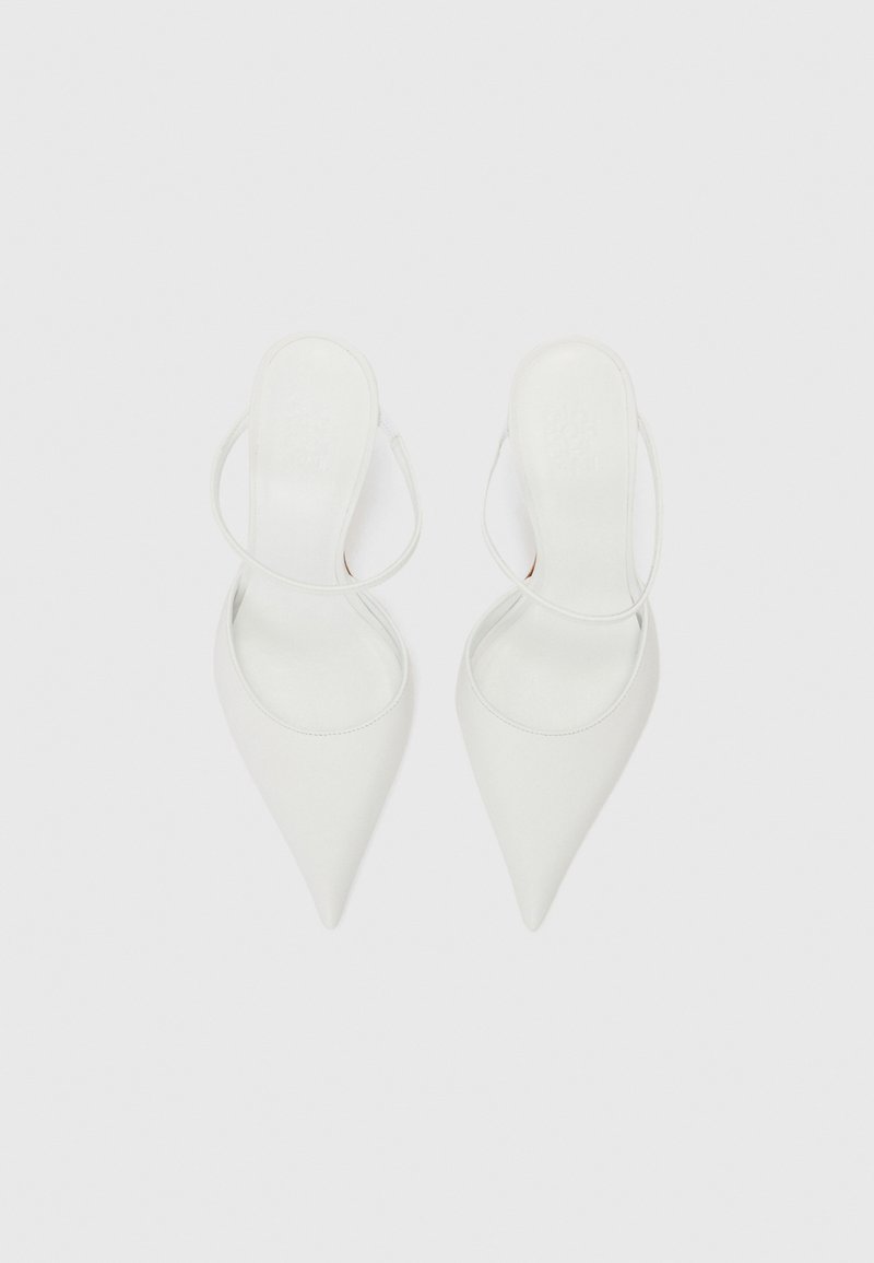 Witte hoge hakken met een puntige neus en slingback ontwerp. Gemaakt van soepel leer met minimale stikdetails. Platte zool.