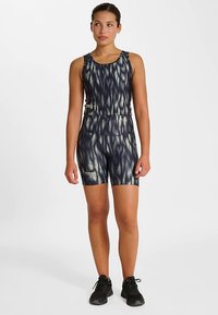 Granatowy i jasnoniebieski sportowy kombinezon z wzorem fal, o dopasowanym kroju, bez rękawów i krótki do połowy ud. Czarne sneakersy.