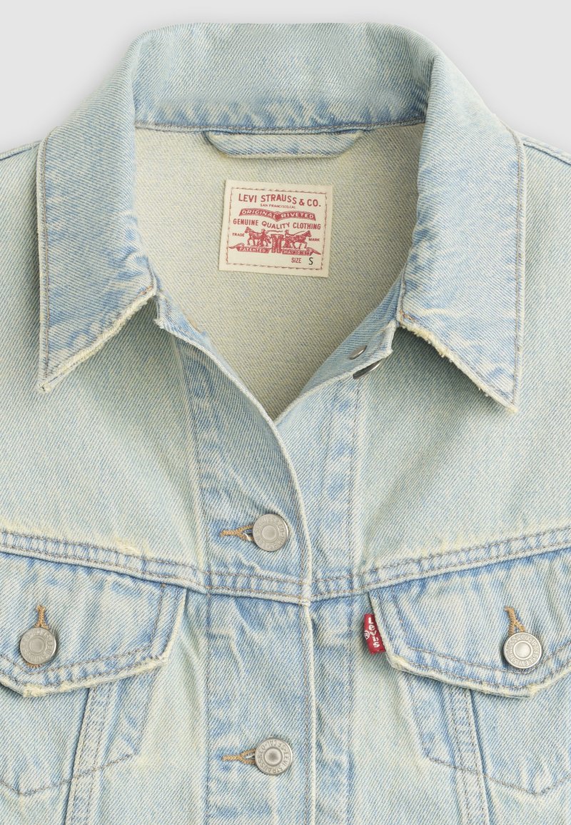 Veste Levi's en denim bleu clair avec boutons en métal, deux poches poitrine, et étiquette d'entretien affichant le logo de la marque et la taille small.
