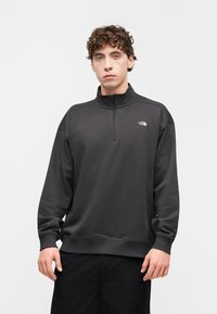 Φούτερ σε σκούρο γκρι, με φερμουάρ στο ένα τέταρτο του λαιμού, ριμπ μανσέτες και λογότυπο στο στήθος. Λεία υφή υφάσματος με άνετη εφαρμογή.