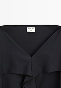 Czarny strój z dekoltem V, z warstwowym wzorem. Zawiera białą metkę z wyraźnym napisem "Massimo Dutti" oraz "Studio".