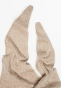 Sciarpa di un beige chiaro, morbida e soffice, con estremità a punta, caratterizzata da una delicata texture a maglia e un leggero lucido. I bordi sono leggermente sfilacciati.