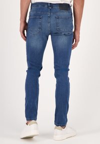 Jeans i denim, blå med blekt tvätt, slim-fit design, raka ben, två bakfickor, matchade med vita sneakers.