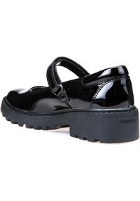 Scarpa Mary Jane in pelle verniciata nera con punta tonda, cinturino regolabile e suola in gomma spessa con un motivo a trama testurizzata.