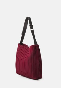 Sac fourre-tout plissé bordeaux avec une surface texturée, détail de couture latérale, et une sangle noire réglable avec une boucle en argent.
