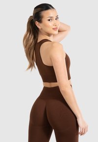 Conjunto de top corto de canalé marrón y leggings con un diseño seamless. La tela, ajustada y elástica, exhibe un acabado texturizado.