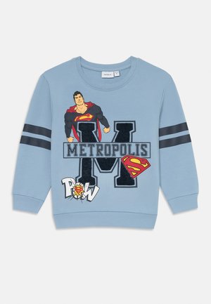 Šviesiai mėlynas medvilninis džemperis su Superman grafika, ženklu "METROPOLIS" ir juodomis juostelėmis ant rankovių.