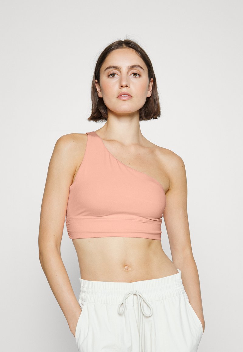 Top cropped assimétrico de um ombro só em tecido rosa suave. Textura suave com um design ajustado, apresentando uma cintura larga para maior conforto.