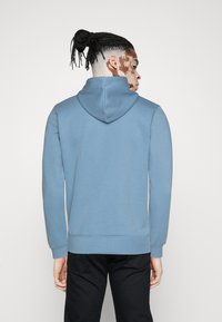 Felpa con cappuccio in morbido tessuto di colore azzurro chiaro. Caratterizzata da maniche lunghe, una tasca a marsupio frontale e polsini e vita a coste.