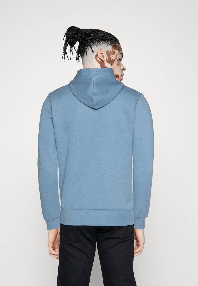 Kapuzensweatshirt aus weichem, hellblauem Stoff. Verfügt über lange Ärmel, eine vordere Kängurutasche sowie gerippte Bündchen und einen gerippten Saum.