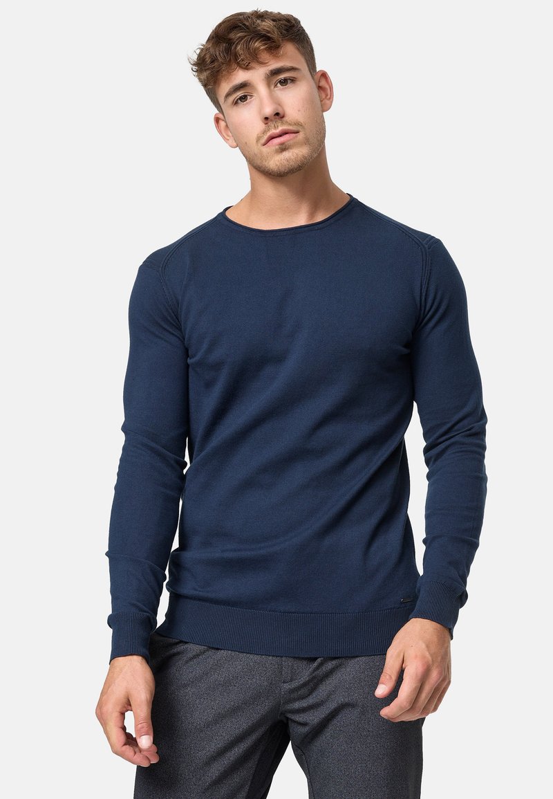 Pullover en tricot bleu marine à manches longues et encolure ronde. Présente des poignets et un ourlet en côtes subtils, mettant en avant une texture lisse.