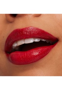 Bright red lips with a glossy finish, showing smooth texture and defined contours, alongside white teeth and a natural skin tone background.