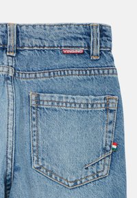 Jeans in denim di colore azzurro chiaro con design standard a cinque tasche. Presenta un'etichetta rossa "VINGINO" e un piccolo accento della bandiera ungherese sulla tasca posteriore.