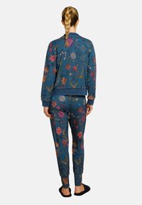 Sweater en joggingbroek set in blauw met veelkleurige bloemenborduursels, voorzien van ribgebreide manchetten en tailleband, en een zachte textuur.