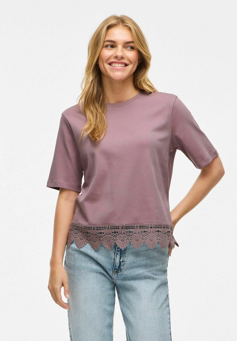 Top de manga corta en mezcla de algodón de color púrpura con un dobladillo de encaje con forma de pico, complementado por un corte relajado y cuello redondo.