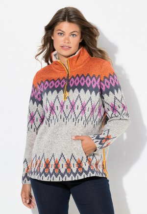 Fleece pullover med høj krave, orange top, mønstret grå krop med lilla og pink geometriske designs, og lomme med lynlås.