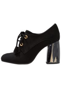 Svart mockasko med rund tå, snörning framtill och dekorativt frans. Har en kraftig, transparent klack med marmorerade mönster.