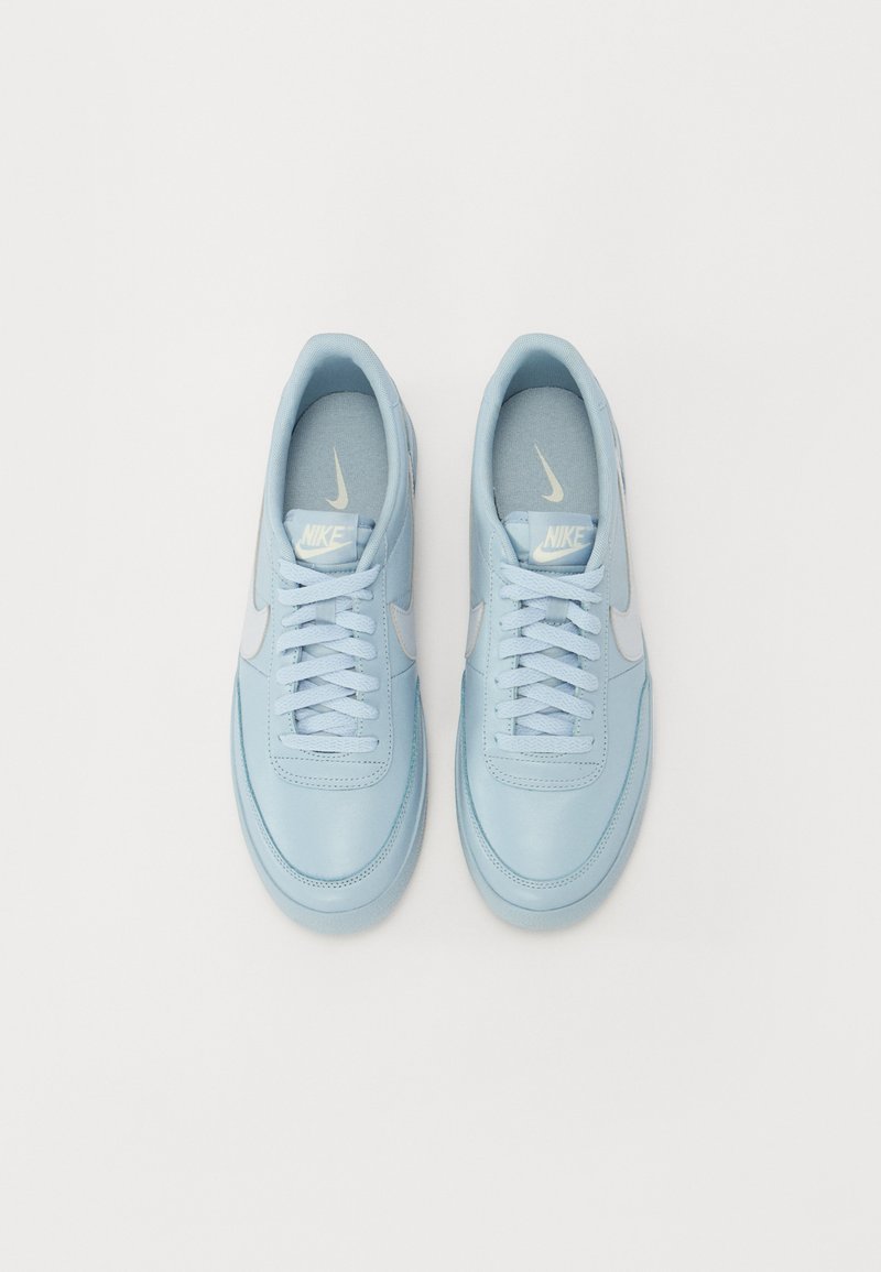 Baskets en cuir bleu clair avec des surfaces texturées, lacets plats et un accent de swoosh Nike blanc. Design minimaliste, bout arrondi lisse.