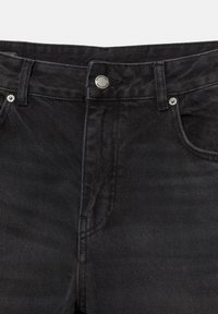 Jeans in denim nero con finitura testurizzata, dotati di chiusura a bottone e tasche frontali. Cuciture sottili accentuano il design.