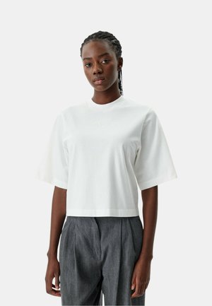 Witte cropped t-shirt met korte mouwen, met een subtiele "PINKO" logo in bijpassende draad. Zachte stof en een ontspannen pasvorm. Gecombineerd met grijze broeken.