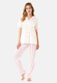 Conjunto de pijama que incluye una parte superior de botones y mangas cortas en blanco con lunares rosas y pantalones de rayas rosas. Tejido suave con un corte relajado.