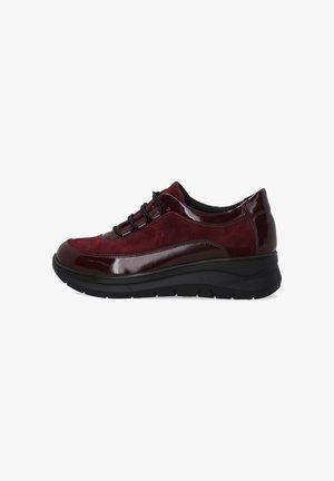 Burgunderfarbene Damensneaker mit Obermaterial aus Wildleder und lackiertem Leder, schwarzen Schnürsenkeln und dicker schwarzer Gummisohle, Seitenansicht auf weißem Hintergrund.