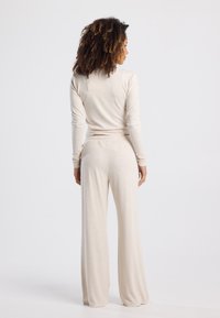 Beige long-sleeve top and matching wide-leg pants made of soft, lightweight fabric. Relaxed fit with an elastic waistband and simple design.