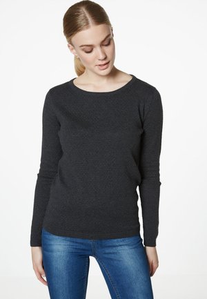 Pull noir à manches longues avec un col rond, fabriqué à partir d'un tissu en tricot texturé. Associé à un jean bleu, créant un look décontracté.