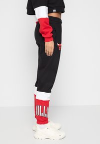 Černé tepláky s červenými a bílými akcenty, zdobené logem "BULLS". Vyrobené z měkkého materiálu s elastickým pasem a manžetami.