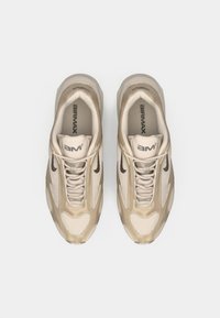 Tenis Nike Air Max bege com um design em malha, acabamentos texturizados, lingueta acolchoada e um logo swoosh escuro em contraste.