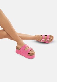 Roze platform sandalen met een kurken zool, met een suède afwerking en twee banden versierd met decoratieve gespen.