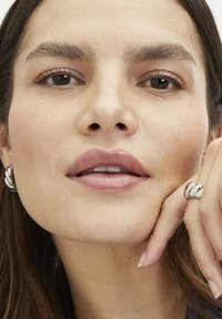 Zilveren creolen met een bladvormig ontwerp en een meerbandring in gepolijst zilver, met gladde, reflecterende oppervlakken.