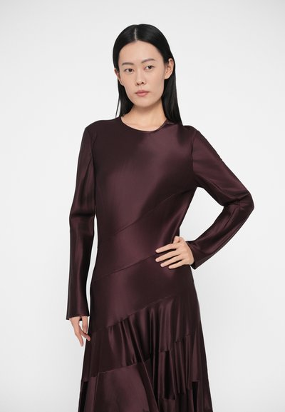Burgundska satenska obleka z dolgimi rokavi, prilegajočim se korzetom in večplastnim, tekočim robom. Ima okrogel izrez in diagonalne šivalne detajle.