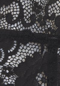 Melnas mežģīņu audums, kas rotāts ar ziedu rakstu un viļņotām malām, demonstrējot smalku sietveida tekstūru un sarežģītus dizaina elementus.