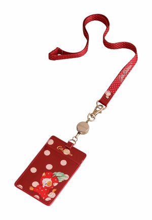 Punane täpiline kaelapael taaskorduva rihmaga ja kaardihoidjaga, millel on kass punase kapuutsiga, kes hoiab lehte, kaubamärgiga Cath Kidston.