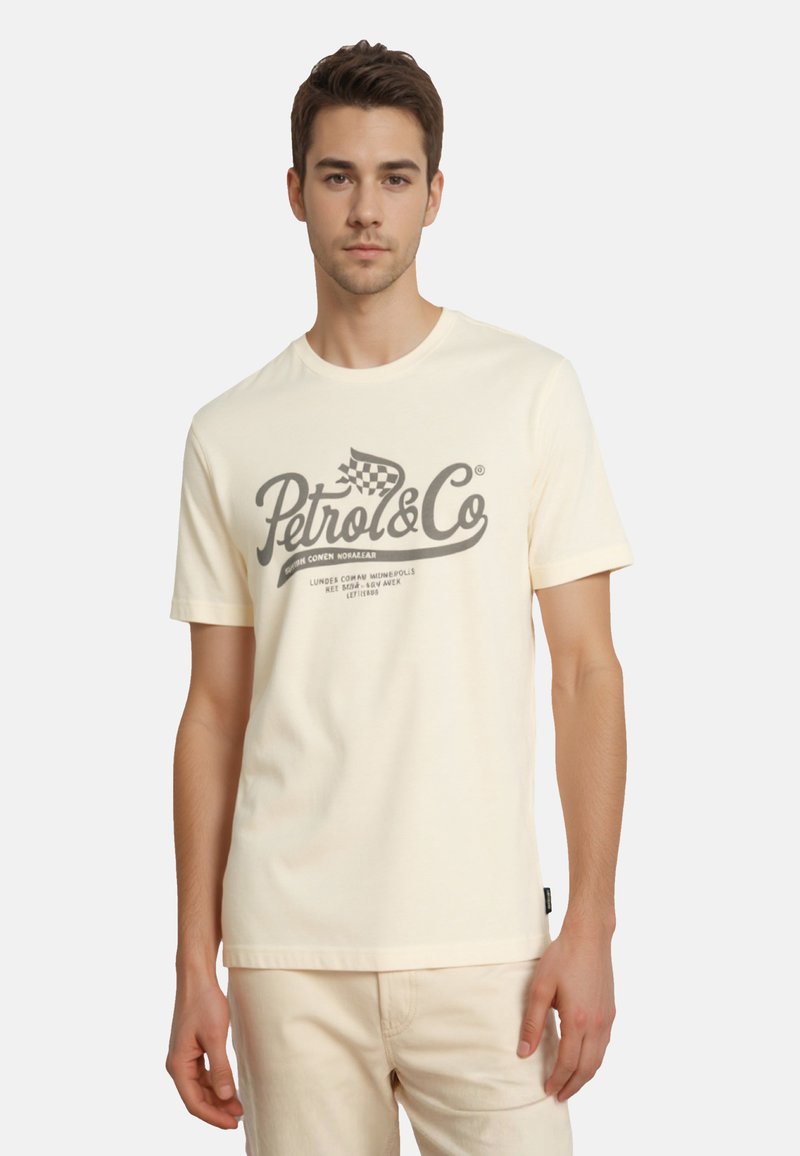 Cremefarvet bomulds t-shirt med et grå grafisk tryk, som inkluderer tekst og ternet flagdesign. Korte ærmer og rund halsudskæring.