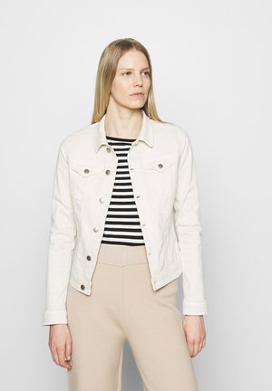 Vit denimjacka med två bröstfickor, silverknappar och en strukturerad passform, kombinerad med en svart- och vitrandig topp och beige byxor.