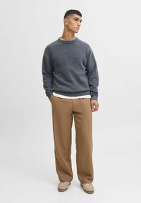 Gray knitted sweater with a round neckline, paired with brown wide-leg trousers and beige shoes. Simple design and textured fabric.