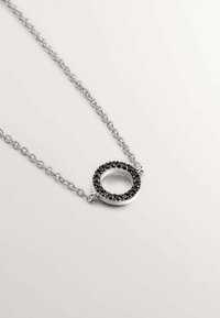 Collar de plata con un colgante circular, que presenta un acento de anillo de piedra negra. La cadena se compone de eslabones ovalados interconectados.