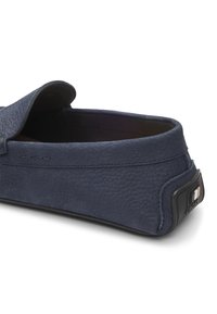 Mocasines para hombre en cuero texturizado color navy, con un perfil bajo, interior acolchado y logo destacado en el talón.